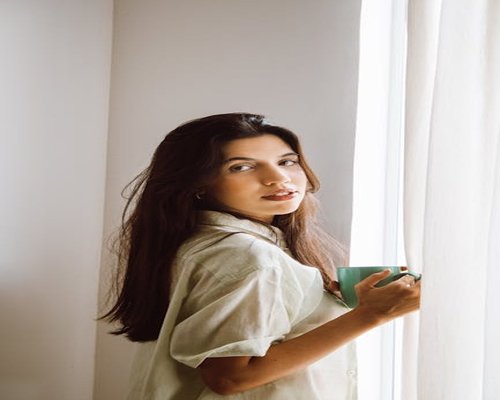 Woman rolling her shoulders gently while holding a coffee mug